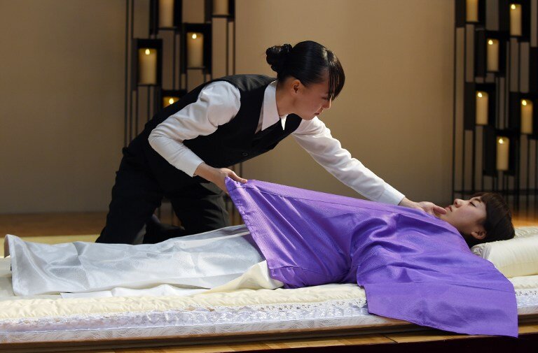 Twenty-seven-year-old Sayuri Takahashi (top) performs her skills in "nokan" -- translated as "encoffinment", or the preparation dead bodies before cremation, during a contest at the Life Ending Industry EXPO 2015 in Tokyo on December 8, 2015. More than 200 companies doing businesses related to the end of life, such as funerals, are participating in the three-day exhibition. Takahashi, the competition winner who was awarded a trophy and an undisclosed sum, said she started her job three years ago after learning about the profession following a death in her own family where the body was attended to by a nokanshi, a specialist in the field. AFP PHOTO / TOSHIFUMI KITAMURA / AFP / TOSHIFUMI KITAMURA